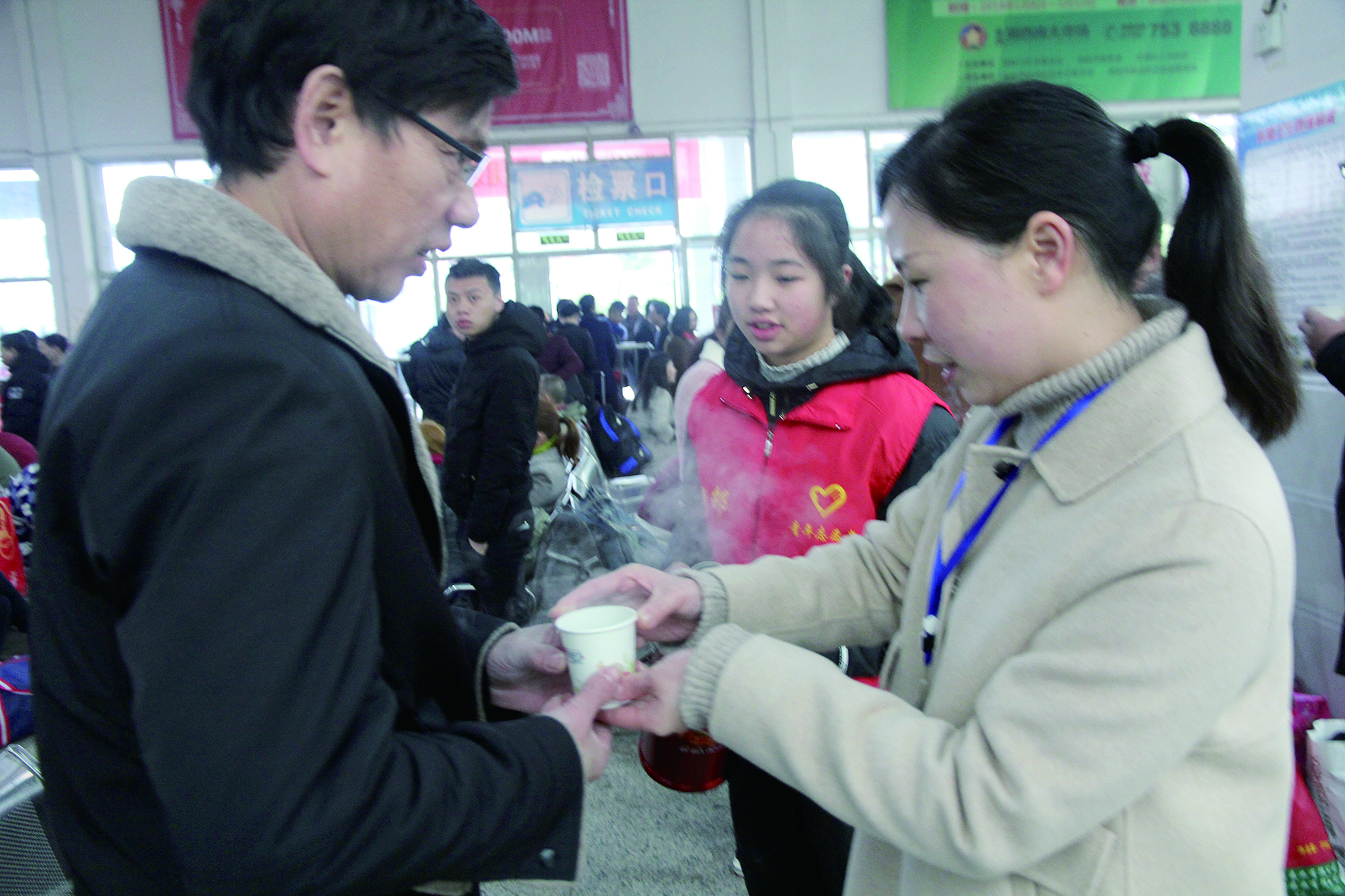 母女服務(wù)春運(yùn) 2月13日，記者在新邵分公司汽車站看到，該分公司安全科副科長李喜梅與其在新邵一中初中部1701班就讀女兒劉嘉怡在車站擔(dān)當(dāng)志愿者。李喜梅在候車室耐心為旅客釋疑解惑，劉嘉怡為旅客遞上一杯杯熱茶，有時(shí)母女也相互合作，其樂融融。 祖冠 攝影報(bào)道